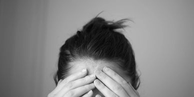 Someone in black and white has their hands on their forehead because they have a headache.