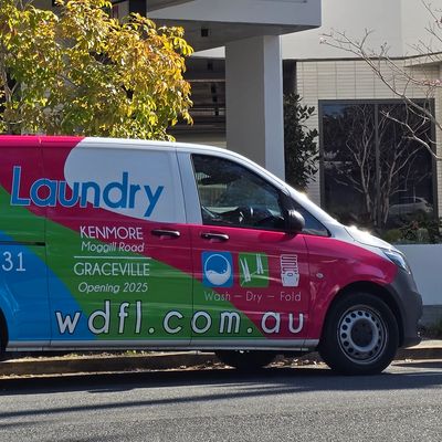 Colorful laundry service van parked on street.