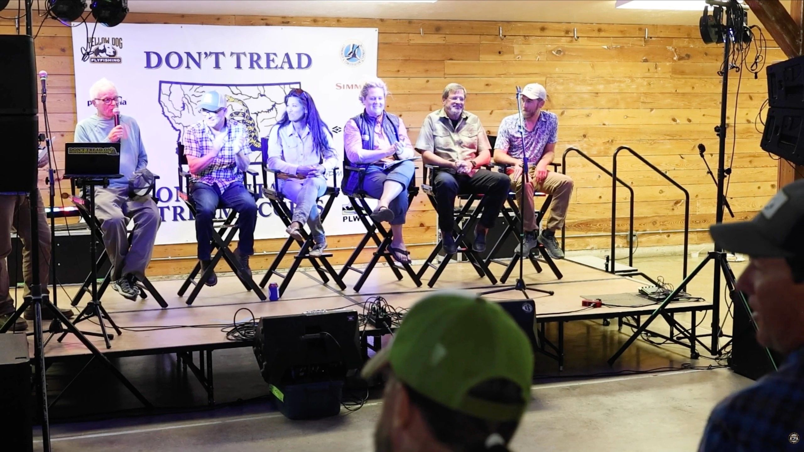 Panel discussion with six speakers on stage in a wooden room.