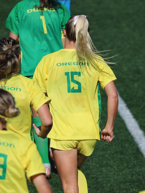 Female soccer players from Oregon Ducks running on the field.