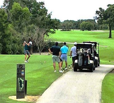 Golfers on a green course with golf carts nearby.