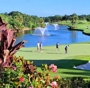 Golfers playing on a lush course with fountains and vibrant flowers.