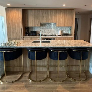 Modern kitchen island with four black and gold stools.