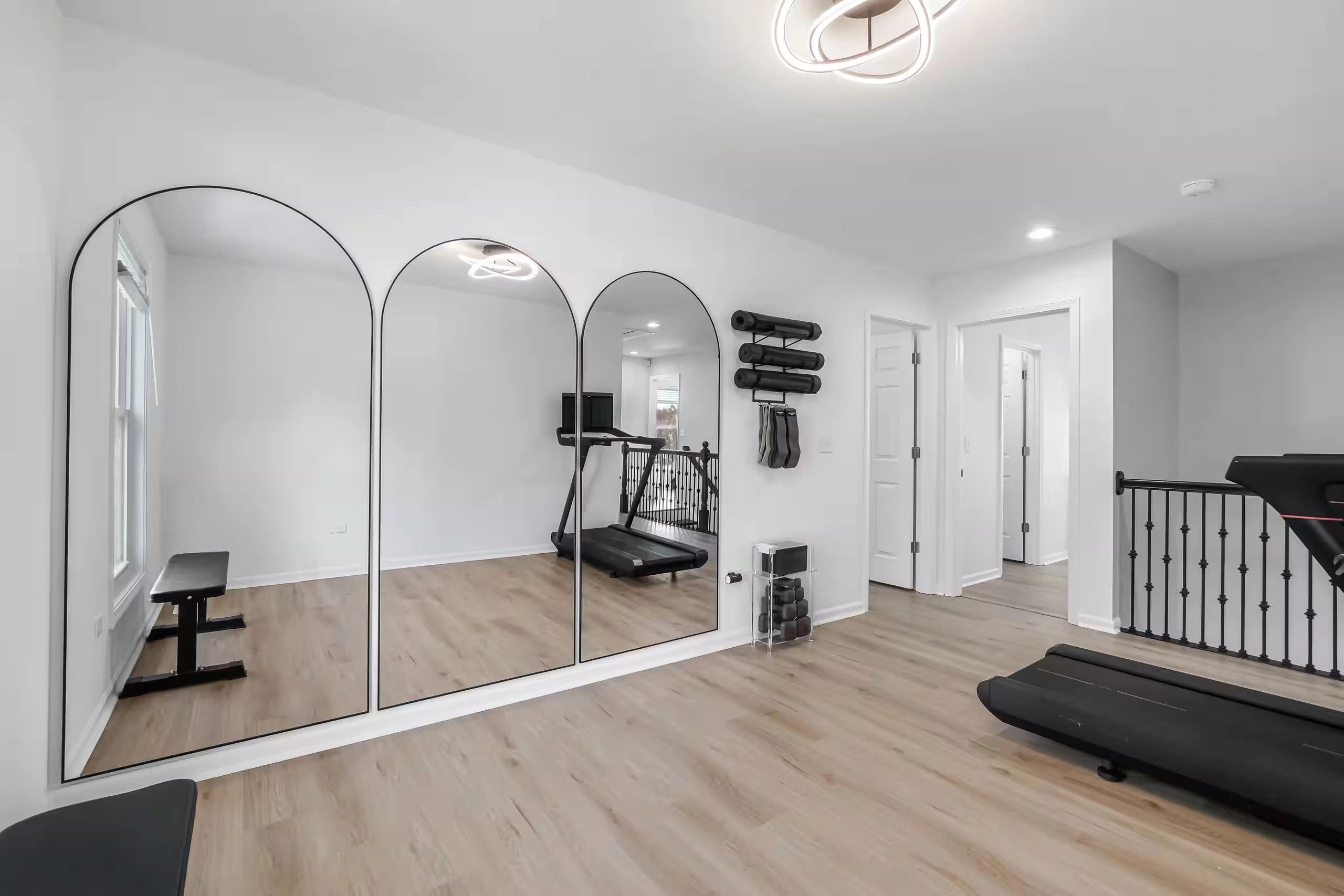 Modern home gym with treadmill and large mirrors.