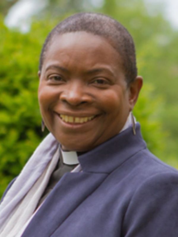 Smiling woman in clergy attire outdoors.