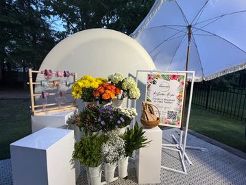 Floral display with colorful flowers and a white umbrella outdoors.