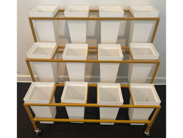 A tiered yellow metal rack with white plastic bins on wheels.