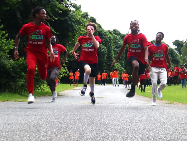 Young people energetically running outdoors wearing matching red shirts.