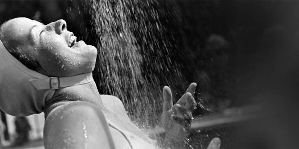 A woman joyfully enjoying a shower or water spray, captured in black and white.