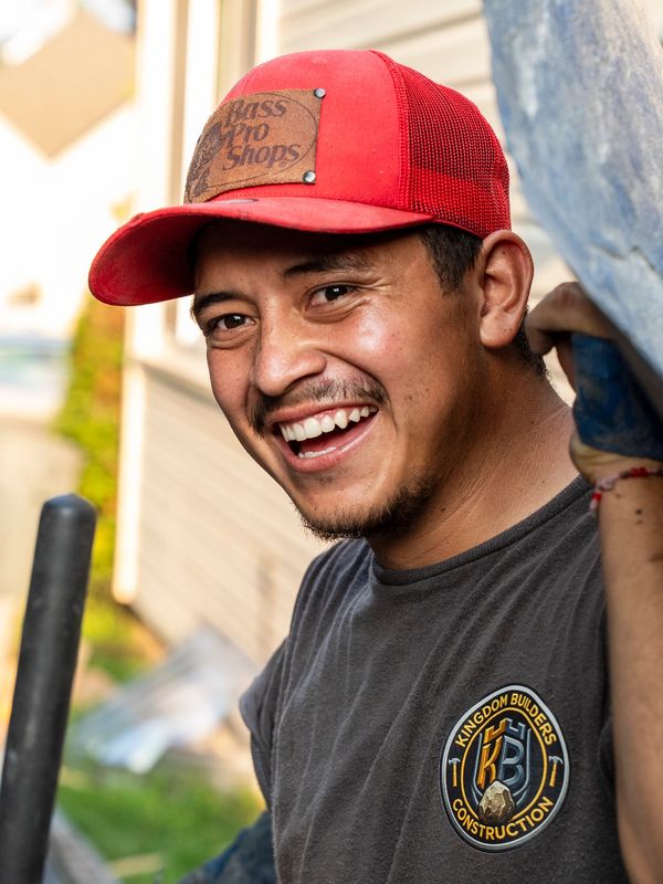 Smiling man in a red cap and construction shirt.