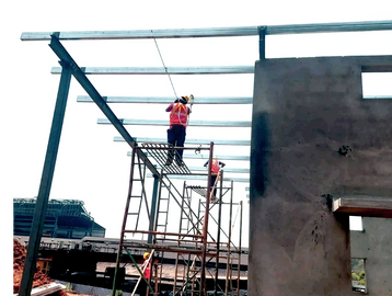 Workers on scaffolding constructing a steel frame roof.