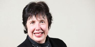 Smiling woman with short dark hair in black attire.