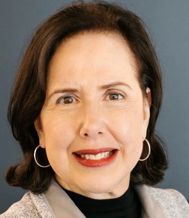Smiling woman with short brown hair and hoop earrings.