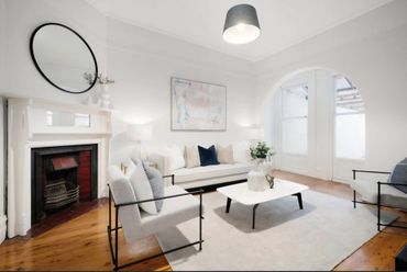 Bright living room with white walls, modern furniture, and wooden flooring.