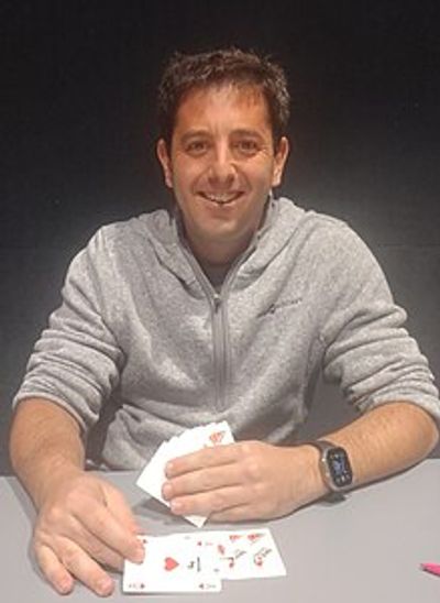 Smiling man playing cards at a table.