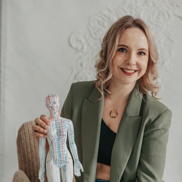 Kobieta trzymająca model ciała ludzkiego z akupunkturowymi punktami.