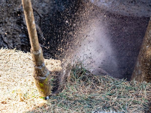 Hydrovac wand blasting water at ground creating a hole while performing underground utility excavation.