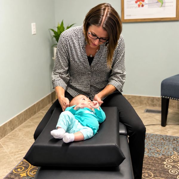 Woman examining a baby lying on a medical table.