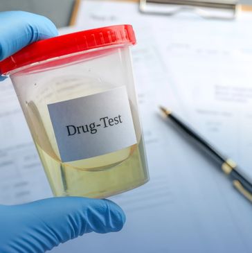 Gloved hand holding a urine sample container labeled 'Drug-Test'.