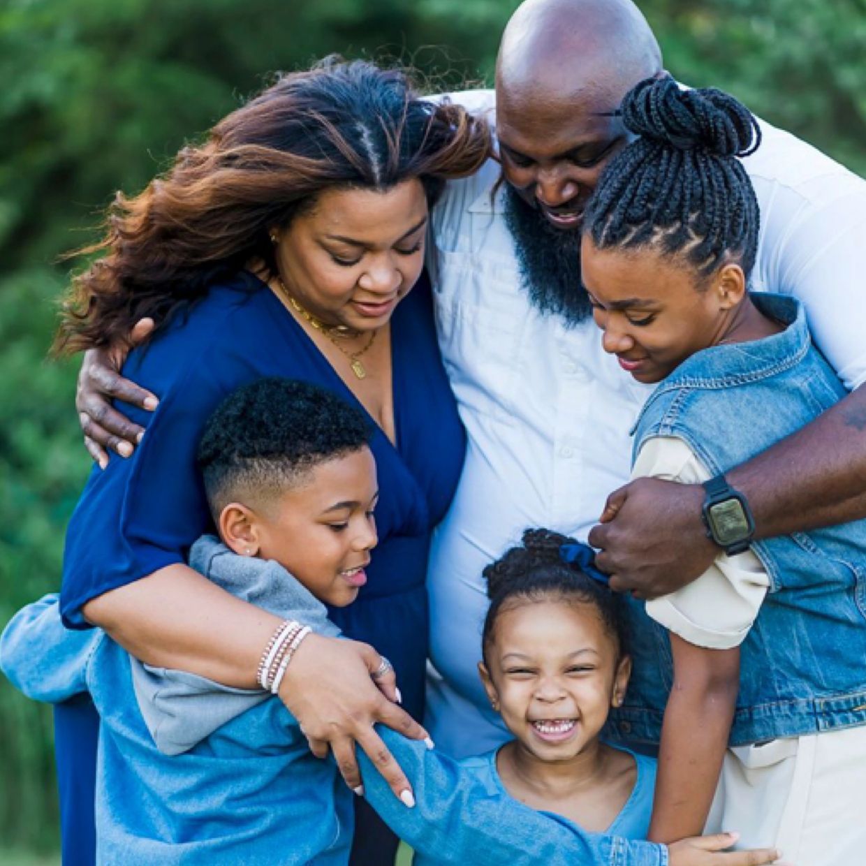 Happy family of six sharing a warm group hug outdoors.