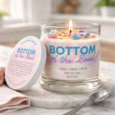 Lit soy wax candle with colorful cereal pieces on top, labeled 'Bottom of the Bowl'.
