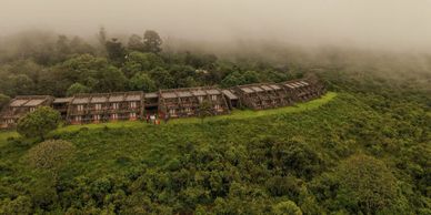 A row of wooden houses on a foggy, lush green hillside.