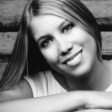 Woman smiling with long hair, resting her arm.