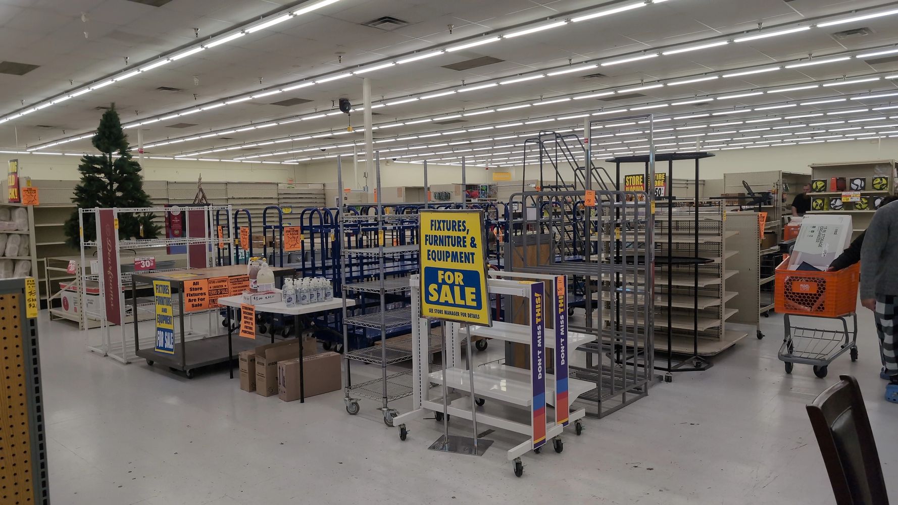 Empty store fixtures and furniture for sale in a large, well-lit warehouse.