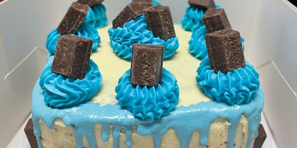 Red Velvet with blue chocolate drizzle and butter cream icing topped with KitKats 