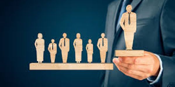 Businessman holding wooden figurine of a leader elevated above others.