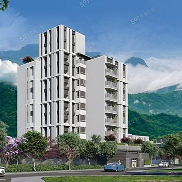 Modern white apartment building with balconies against a mountain backdrop.