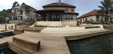 Waterfront house with a spacious wooden dock and stairs leading to the water.