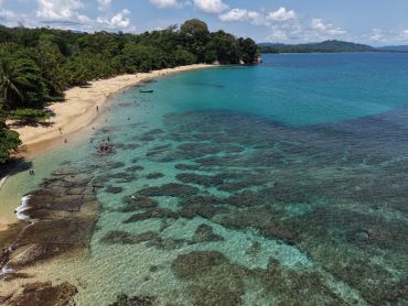 Playa tropical con aguas cristalinas y arrecifes.