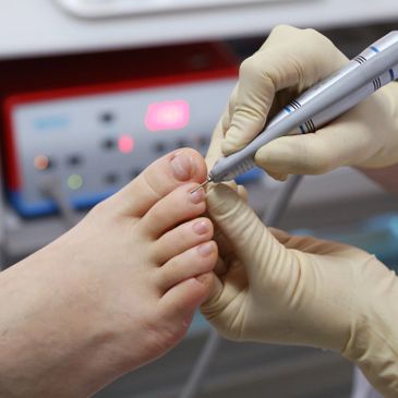 Close-up of a professional performing a foot care procedure on toenails.