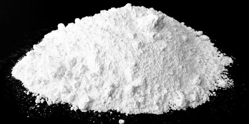 A pile of fine white powder on a black surface.