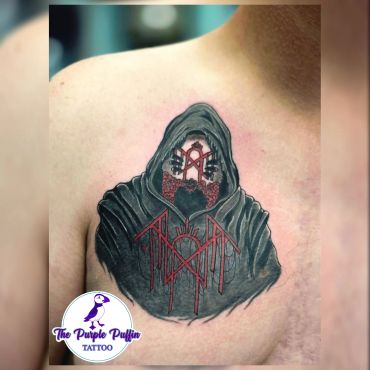 Hooded figure tattoo with intricate red and black details.