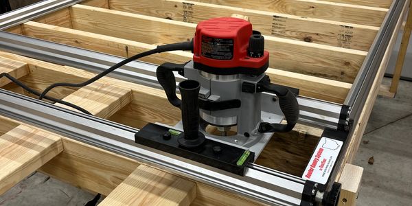 A red router mounted on a track system over a wooden frame.