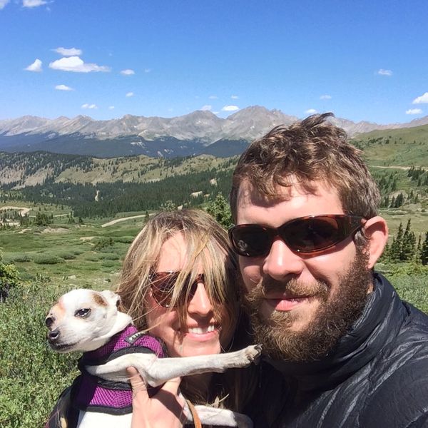 Couple with a small dog enjoying a sunny mountain hike.