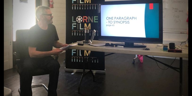 Man presenting a film synopsis on a screen during a workshop.