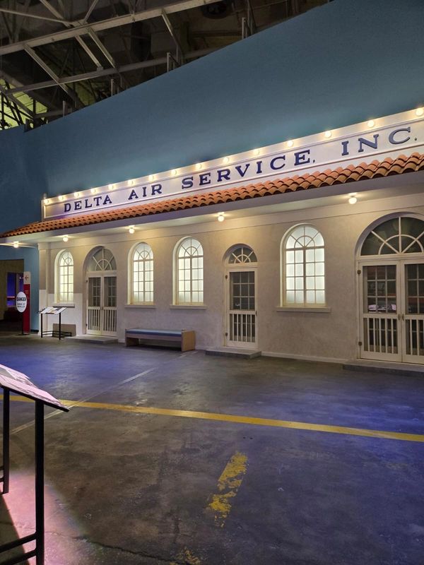 Indoor replica of a vintage Delta Air Service building with lit windows and sign.
