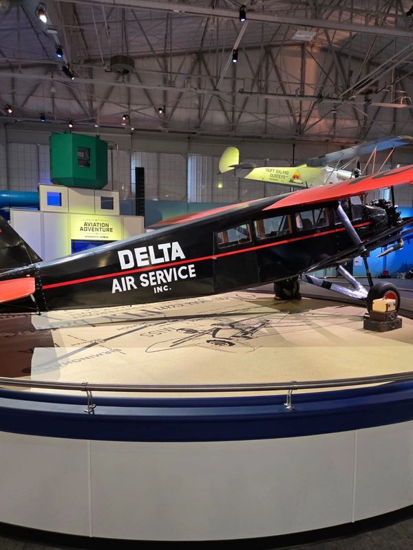 Vintage Delta Air Service airplane displayed in a museum exhibit.