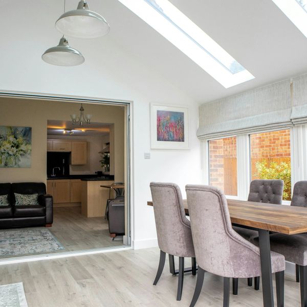 Bright dining area with purple chairs and skylight, adjacent to a cozy living room and kitchen.