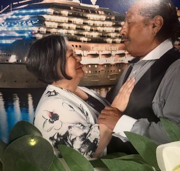 Couple sharing a loving moment with a cruise ship backdrop at night.
