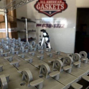Rows of gray metal gaskets in a workshop.