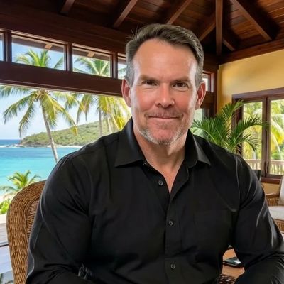 Man sitting indoors with tropical view outside.