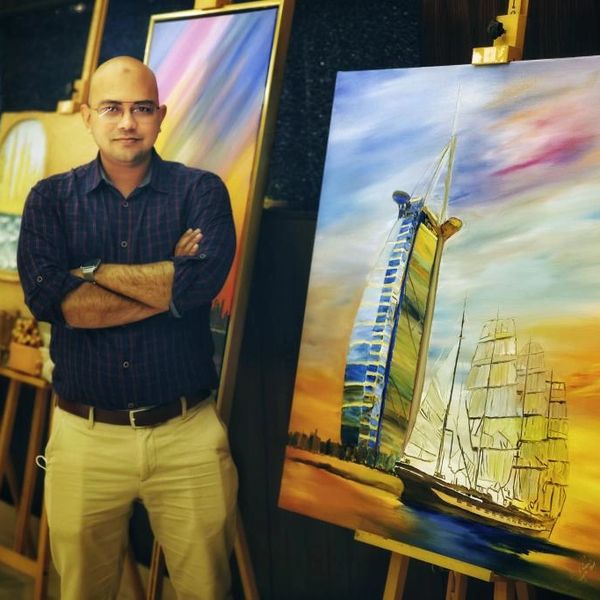 Mahfuzur Rahman, an artist from Bangladesh, poses in front of his painting in Dubai art exhibition