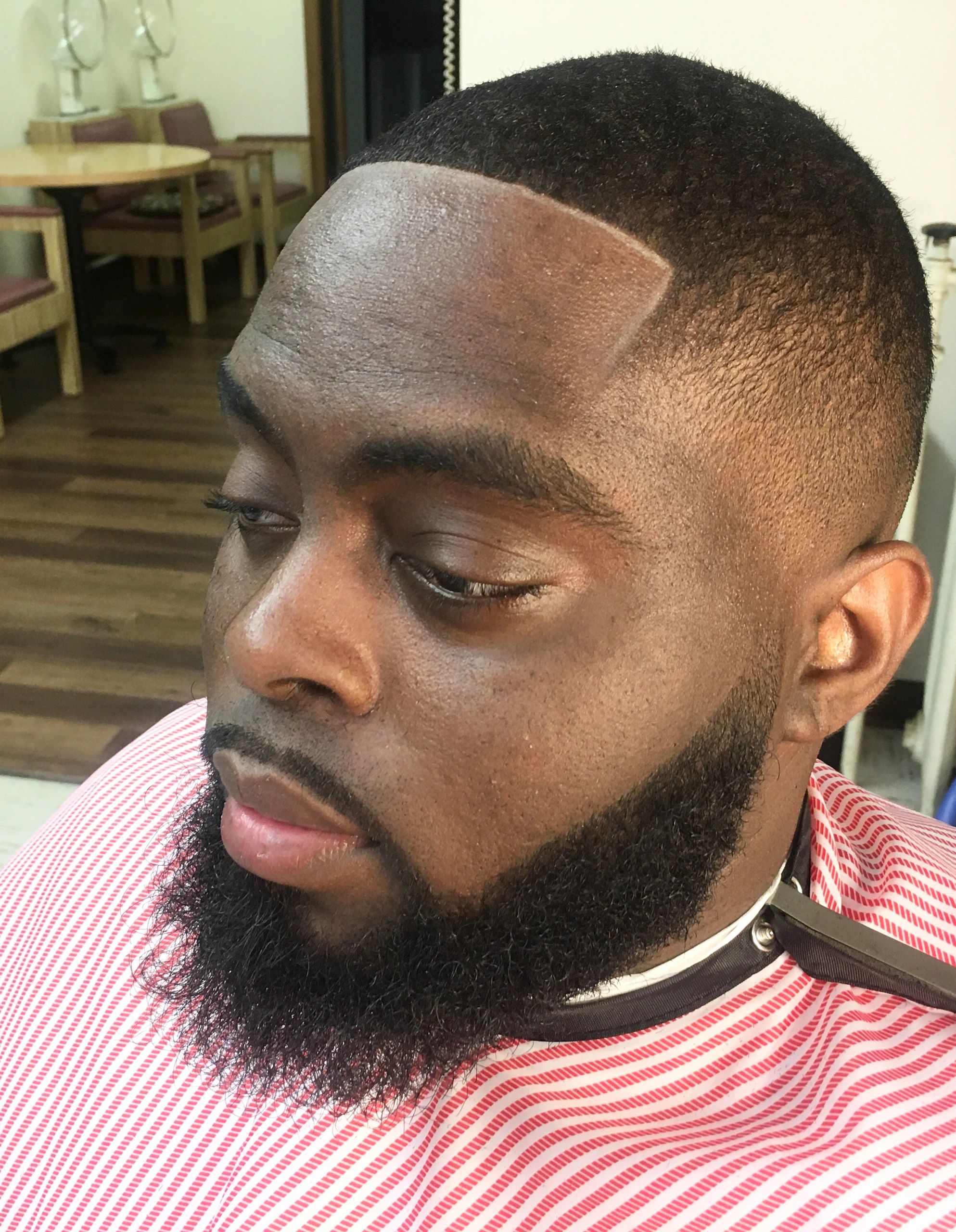 Close-up of a man with a sharp, clean haircut and well-groomed beard.