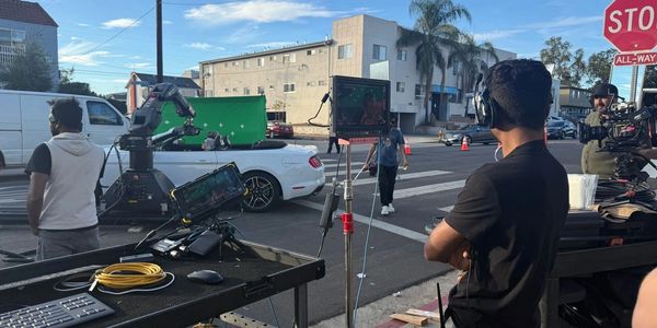 Film crew working on a street scene with equipment and cameras.