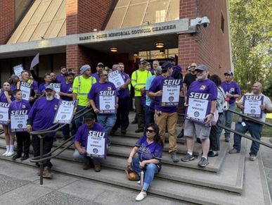 Group of people outside a council chamber with SEIU signs.