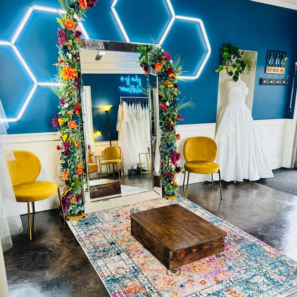 Bright bridal boutique with floral mirror frame and elegant wedding dress.